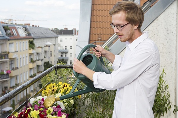 Muž zalievanie kvetín na balkóne