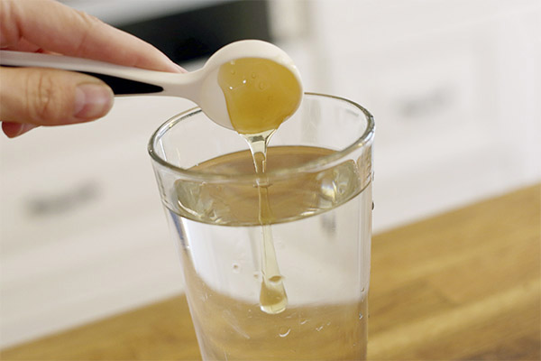 Добавяне на мед към чаша вода
